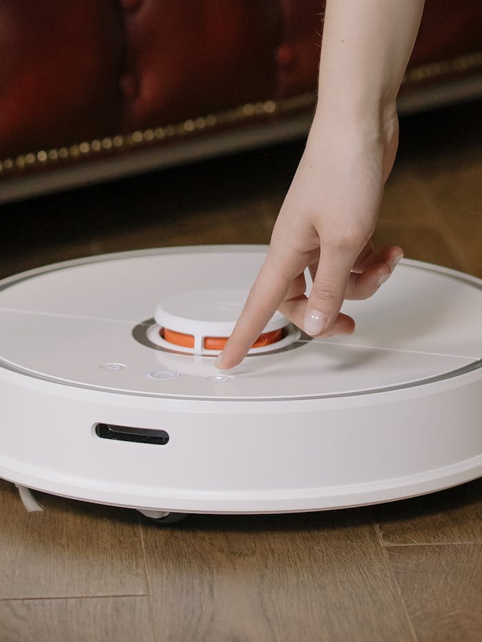 Close-up of a hand interacting with a smart robot vacuum cleaner in a cozy home environment.
